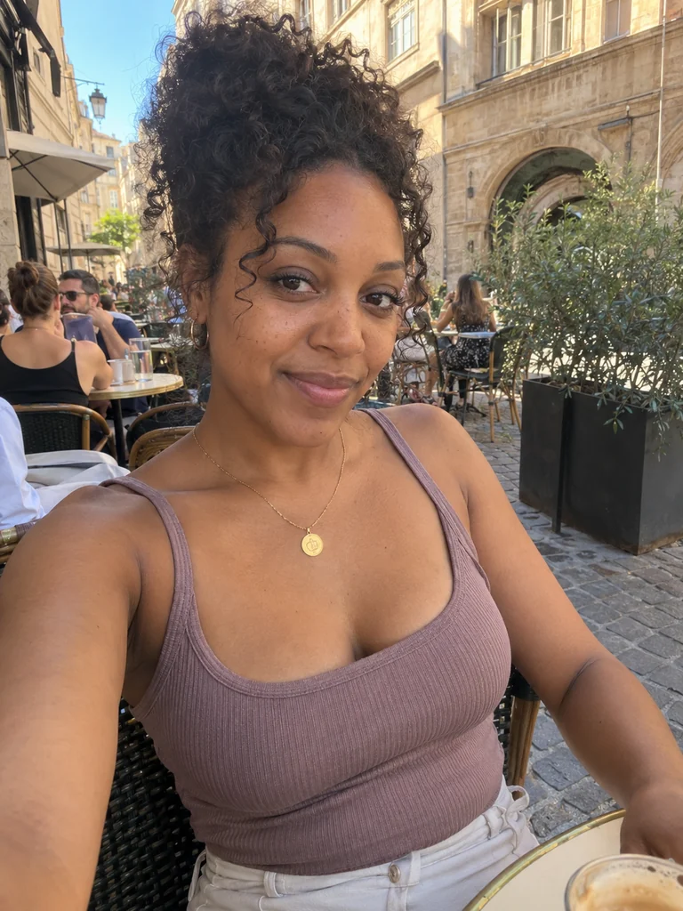 Illustration IA : femme adulte fictive aux cheveux bouclés, en terrasse d’un café lyonnais.